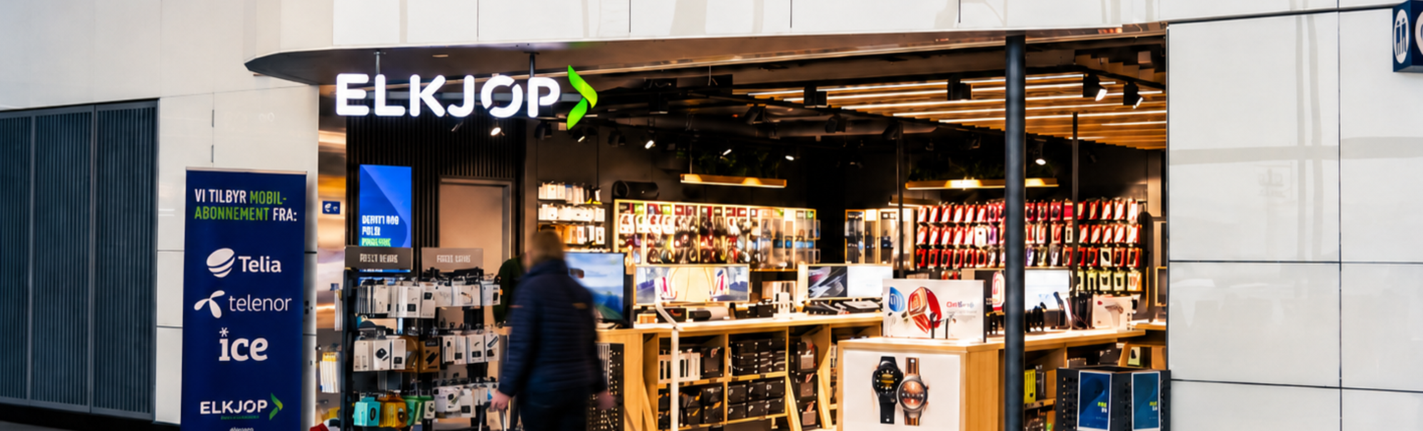 Store employee assisting a customer with earphones in a modern electronics shop, surrounded by phone accessories