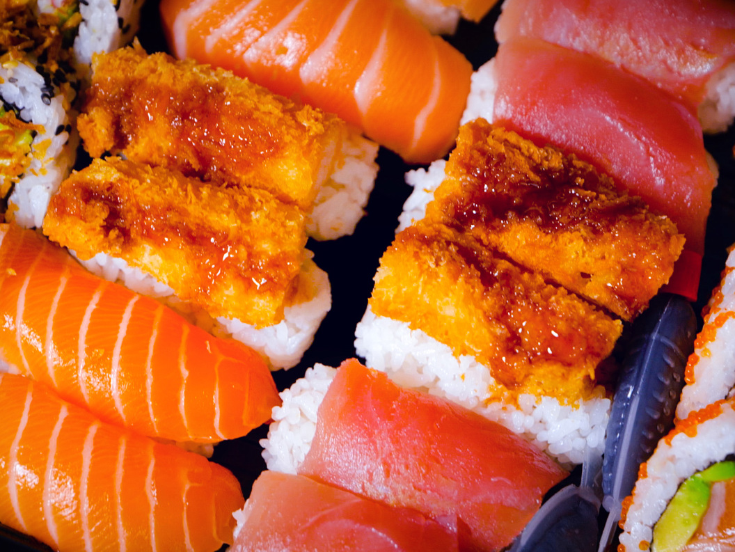 Assorted sushi platter with salmon nigiri, tuna nigiri, crispy shrimp tempura rolls, and fresh avocado rolls