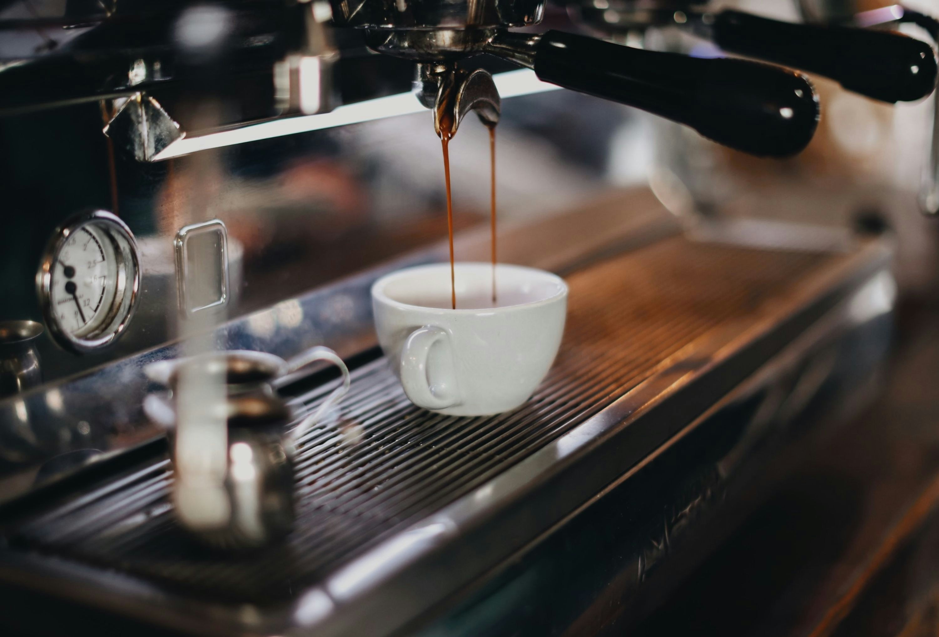 Espresso machine pouring fresh coffee into a white ceramic cup in a cozy cafe setting