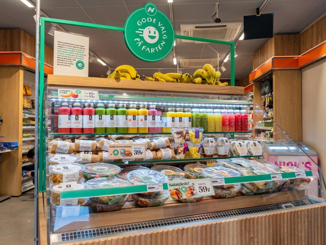 Moderne WHSmith-kiosk på en flyplass som tilbyr bekvemmelighetsartikler, snacks og drikkevarer under levende belysning