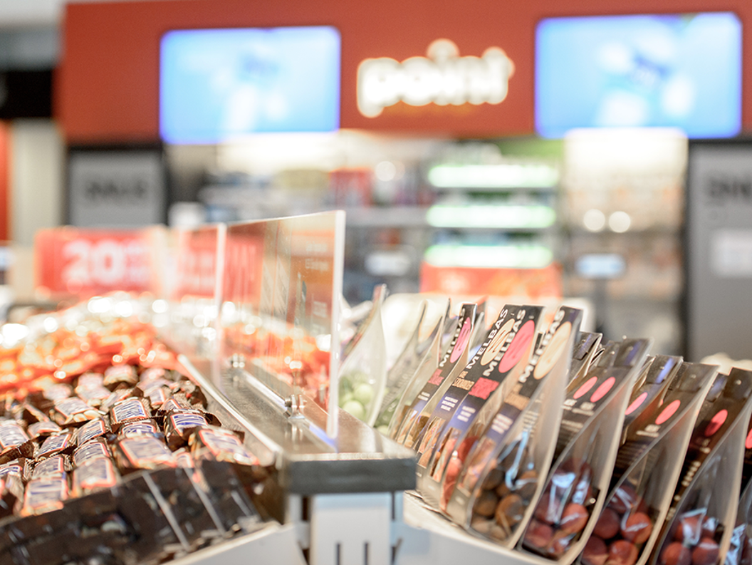 Snop og sjokolade i butikkhylle hos kiosk, med lys og klare fargar i bakgrunnen