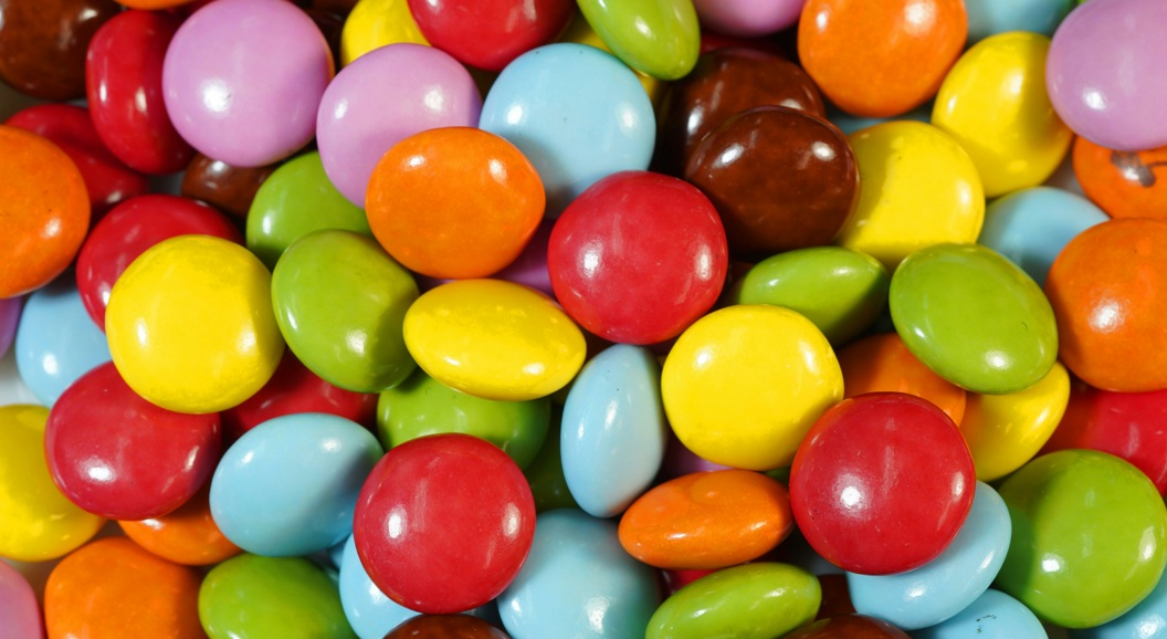 Colorful candy-coated chocolates in varying shades of red, yellow, green, blue, purple, orange, and brown