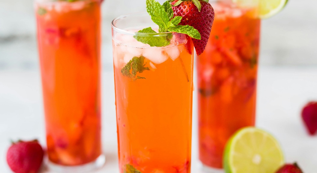 Refreshing strawberry mojito cocktails with mint leaves and lime slices, served in tall glasses on a light background