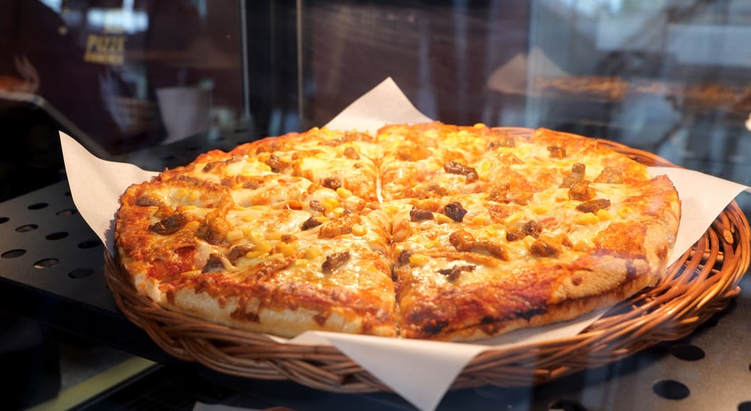 Pizza med ost, kjøtt og sopp servert i ei kurv