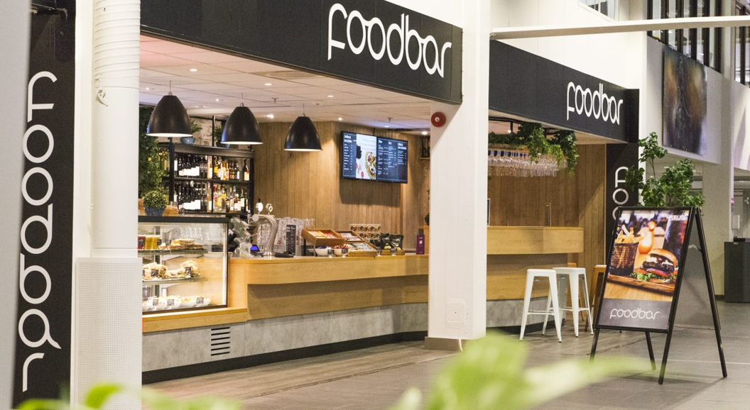 Moderne kafé med serveringsdisk, svart interiør, og digital meny