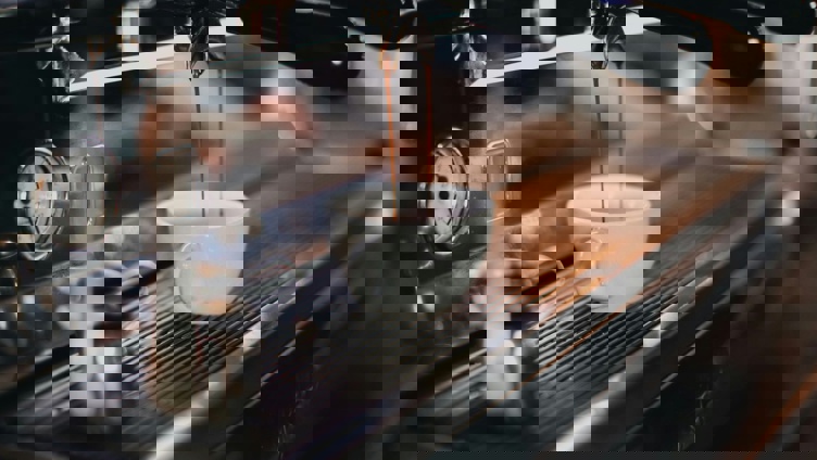 Espressomaskin som heller fersk kaffe i en hvit keramikkkopp i en koselig kaféomgivelse