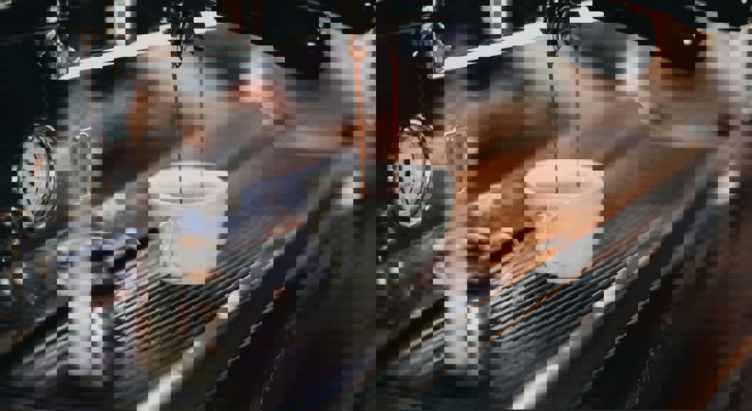 Espresso machine pouring fresh coffee into a white ceramic cup in a cozy cafe setting