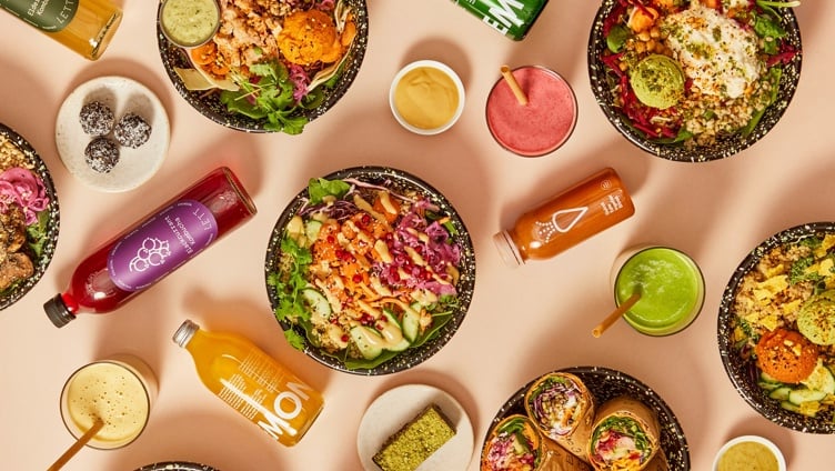 Assorterte sunne boller, wraps og drikker på en lys bakgrunn, med friske grønnsaker, korn og fargerike juicer. Ideell for et næringsrikt måltid