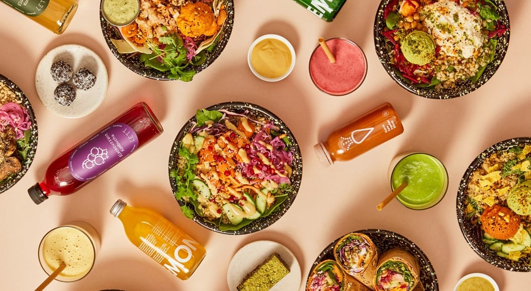 Assorterte sunne boller, wraps og drikker på en lys bakgrunn, med friske grønnsaker, korn og fargerike juicer. Ideell for et næringsrikt måltid