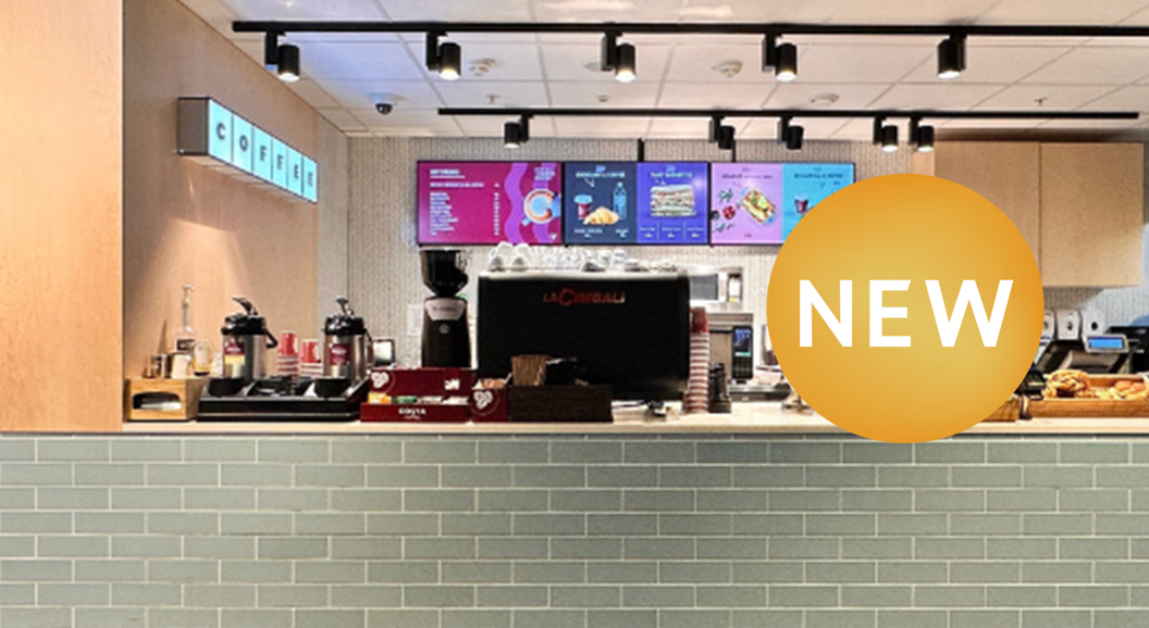 Ny kafé med moderne interiør, kaffemaskin og meny på skjermar