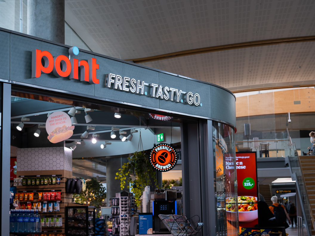 Butikk ved flyplass inngang med skiltet "Point: Fresh. Tasty. Go." Visning av produkter og mattilbud innendørs