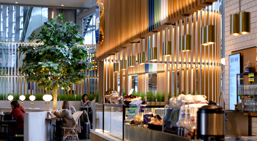 Moderne kaféinteriør med hengande lamper, planter og folk som sit ved bord