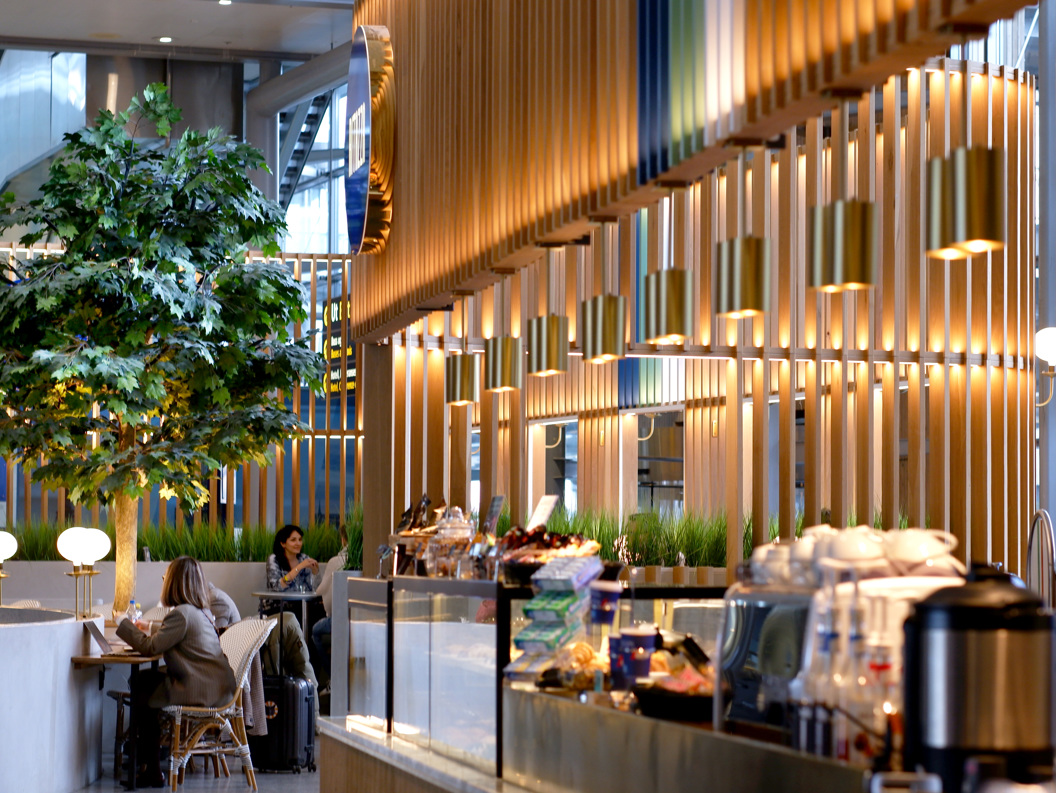 Moderne kaféinteriør med hengande lamper, planter og folk som sit ved bord