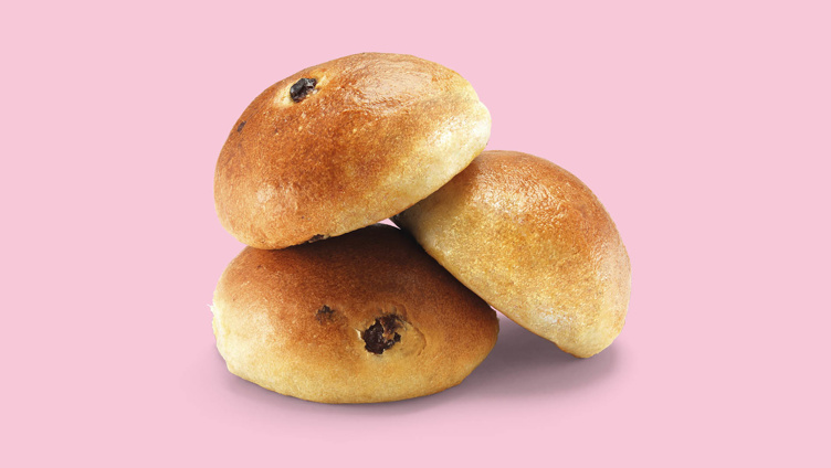 Tre luftige rosinboller på rosa bakgrunn