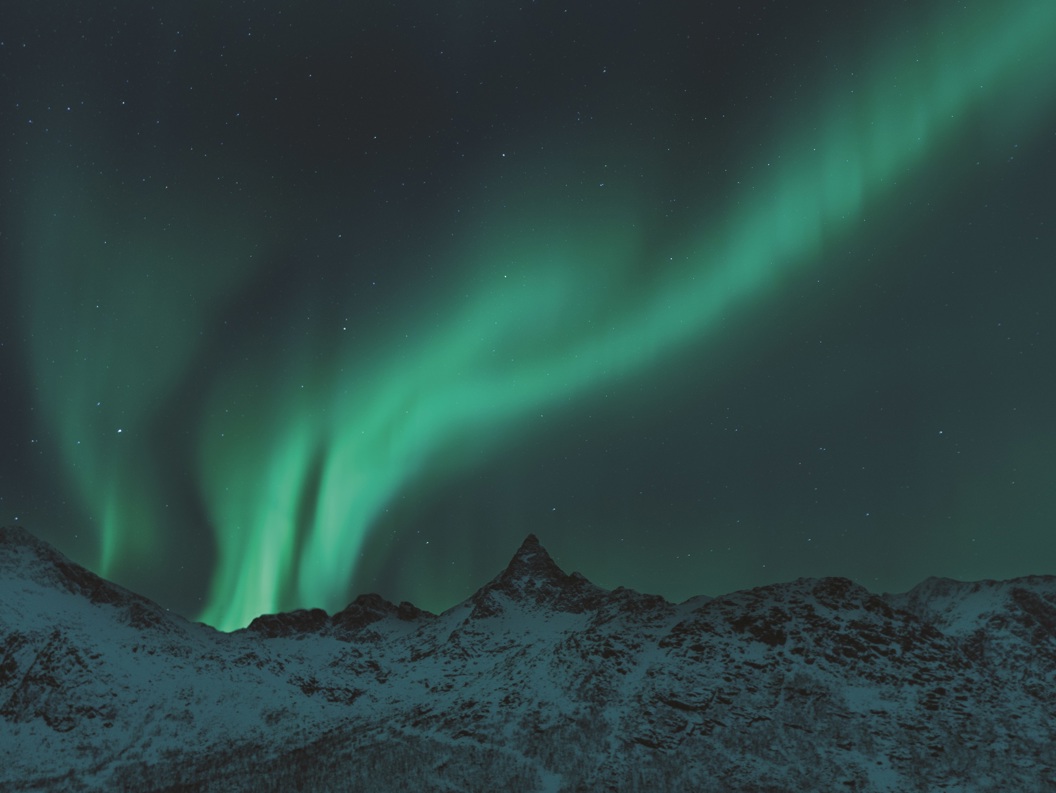 Nordlys over snødekte fjell i en klar nattehimmel