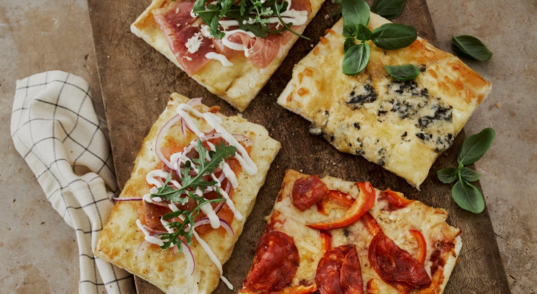 Fire forskjellige pizzastykke på trefjøl