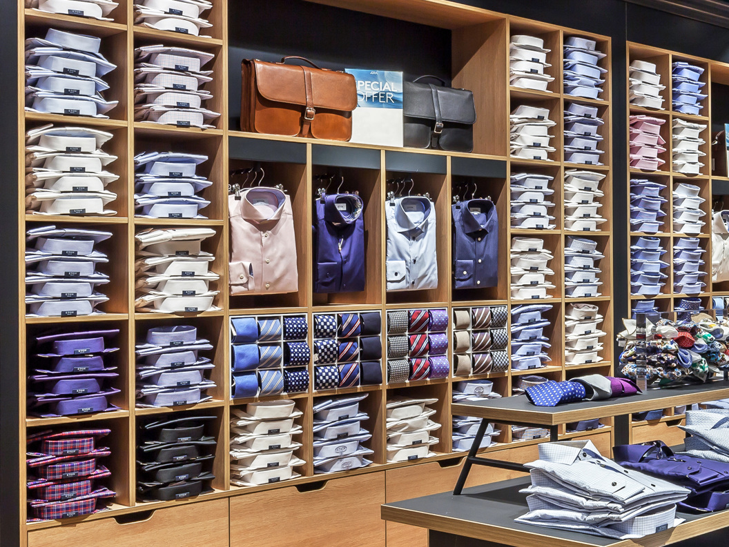 Visning av Eton-skjorter, slips og vesker i et stilfullt butikkmiljø, med pent organiserte klær og tilbehør på trehyller