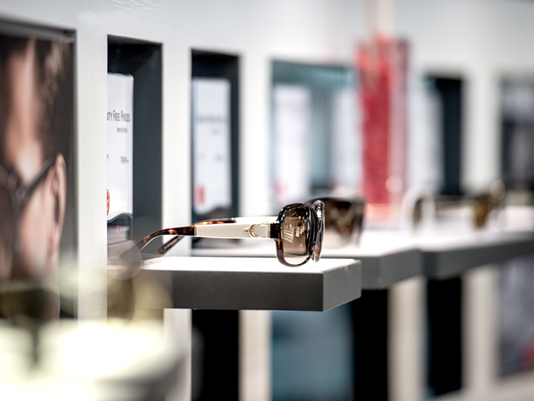 Sunglasses displayed on sleek shelves in a modern eyewear store, highlighting a stylish and contemporary shopping environment