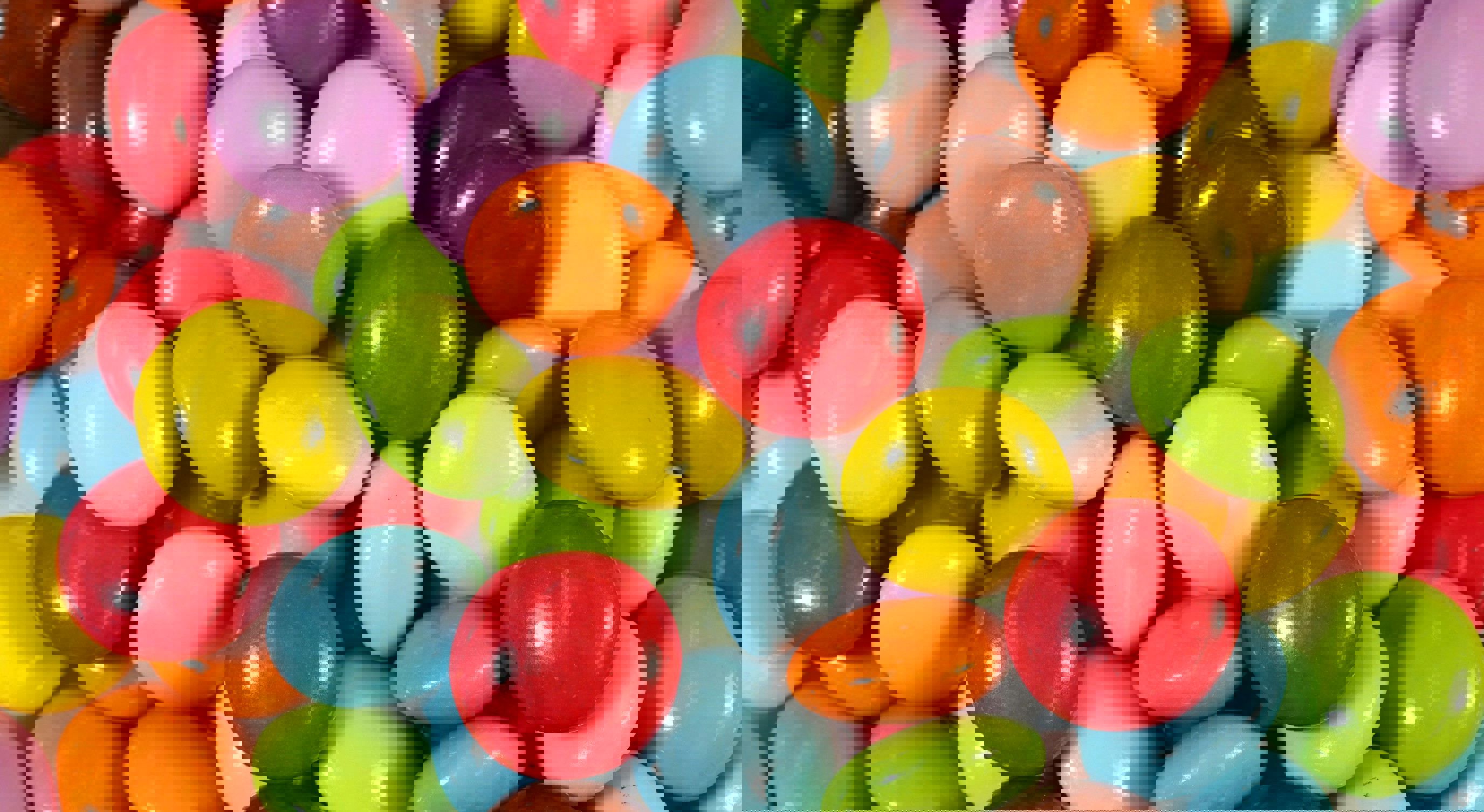 Colorful candy-coated chocolate pieces in various vibrant shades of red, blue, yellow, green, orange, and purple