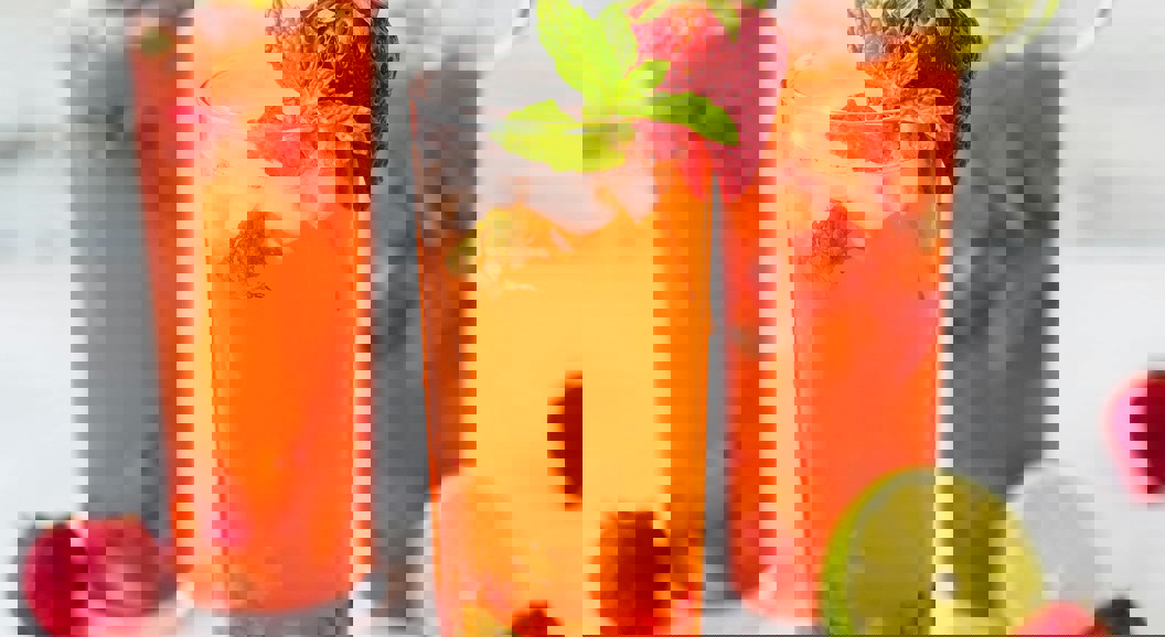 Forfriskende jordbærmojito-cocktailer med mynteblader og limeskiver, servert i høye glass på en lys bakgrunn