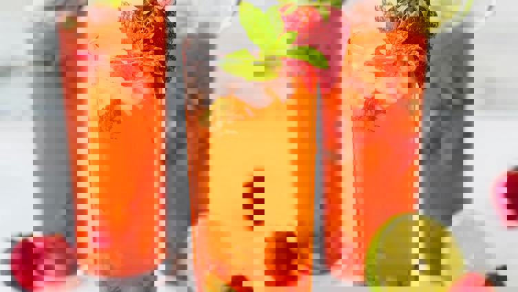 Forfriskende jordbærmojito-cocktailer med mynteblader og limeskiver, servert i høye glass på en lys bakgrunn