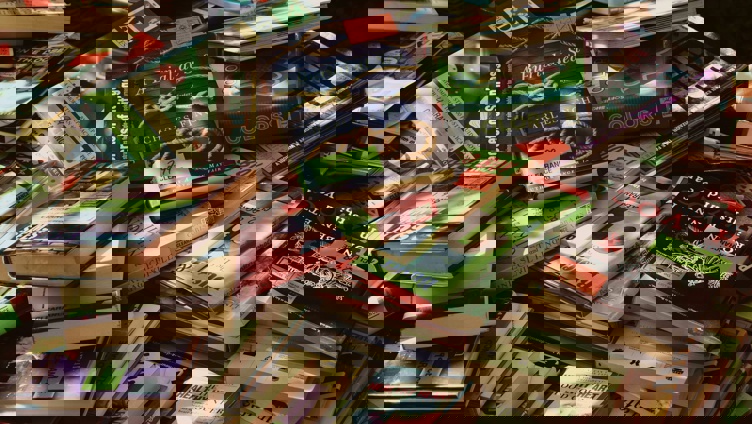 Pile of assorted books with colorful covers on a clearance sale table, featuring various genres and titles