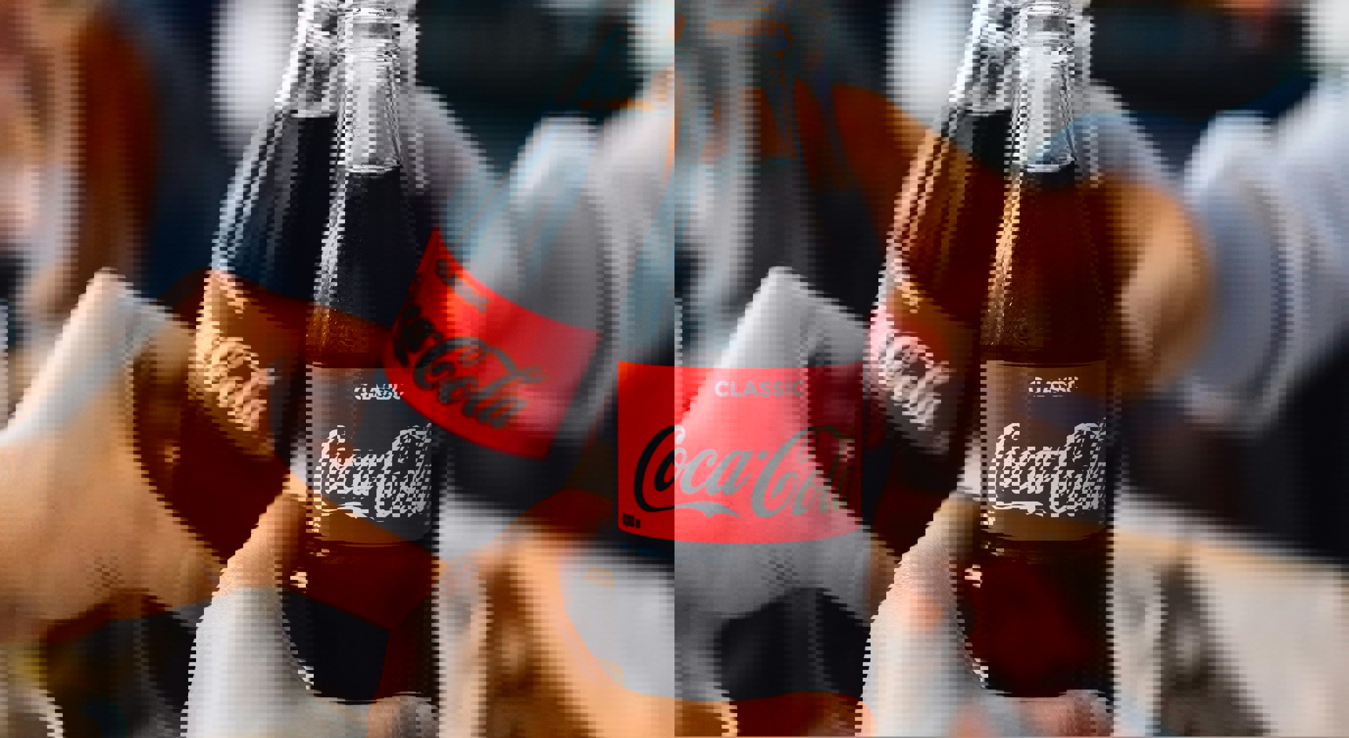 Three people toasting with Coca-Cola bottles in a casual setting, emphasizing social connection and enjoyment