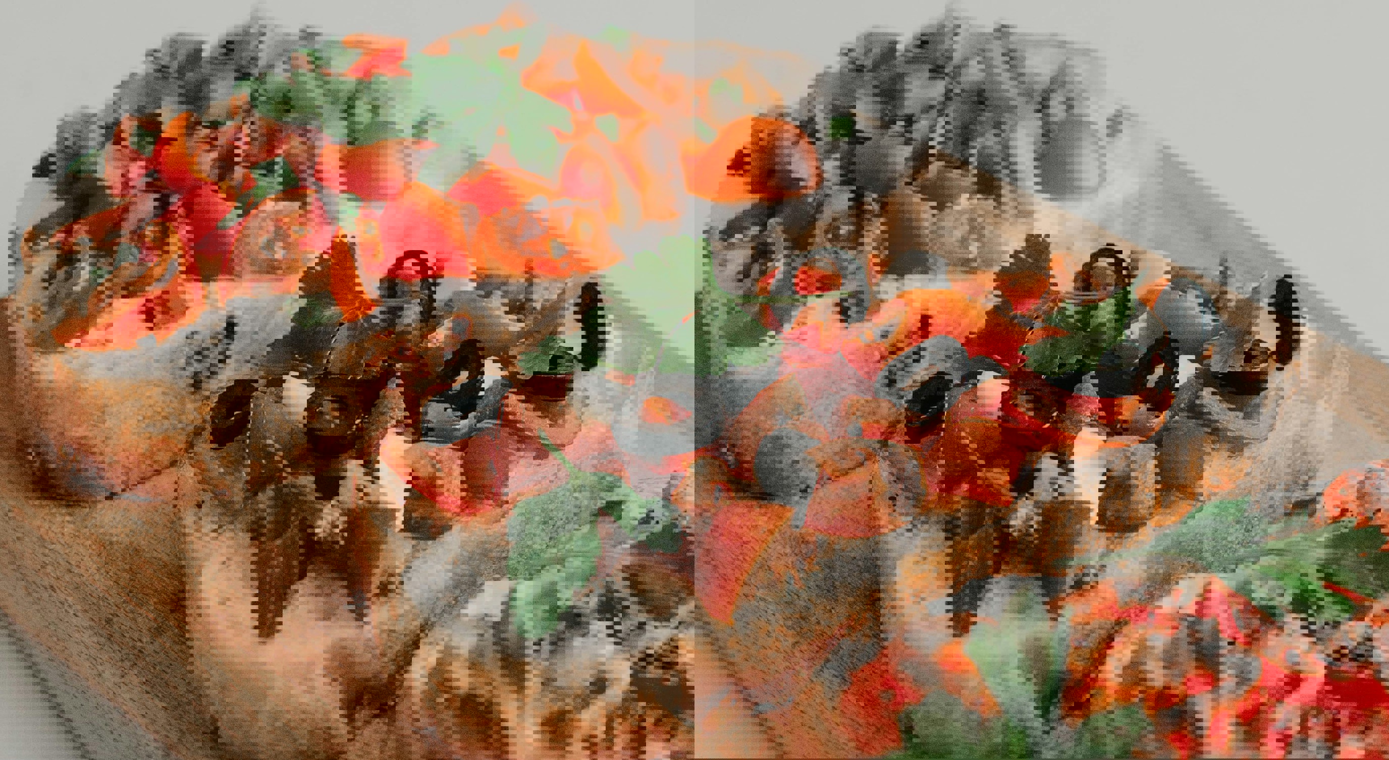 Tre skiver surdeigsbrød med kremost, cherrytomater, sorte oliven og fersk persille på en treplate