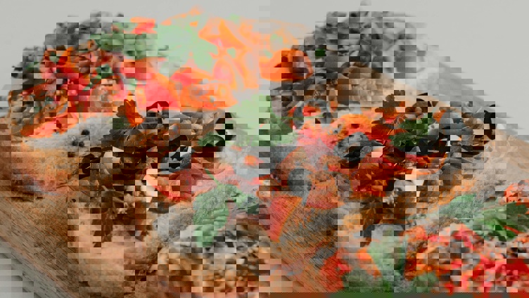 Tre skiver surdeigsbrød med kremost, cherrytomater, sorte oliven og fersk persille på en treplate