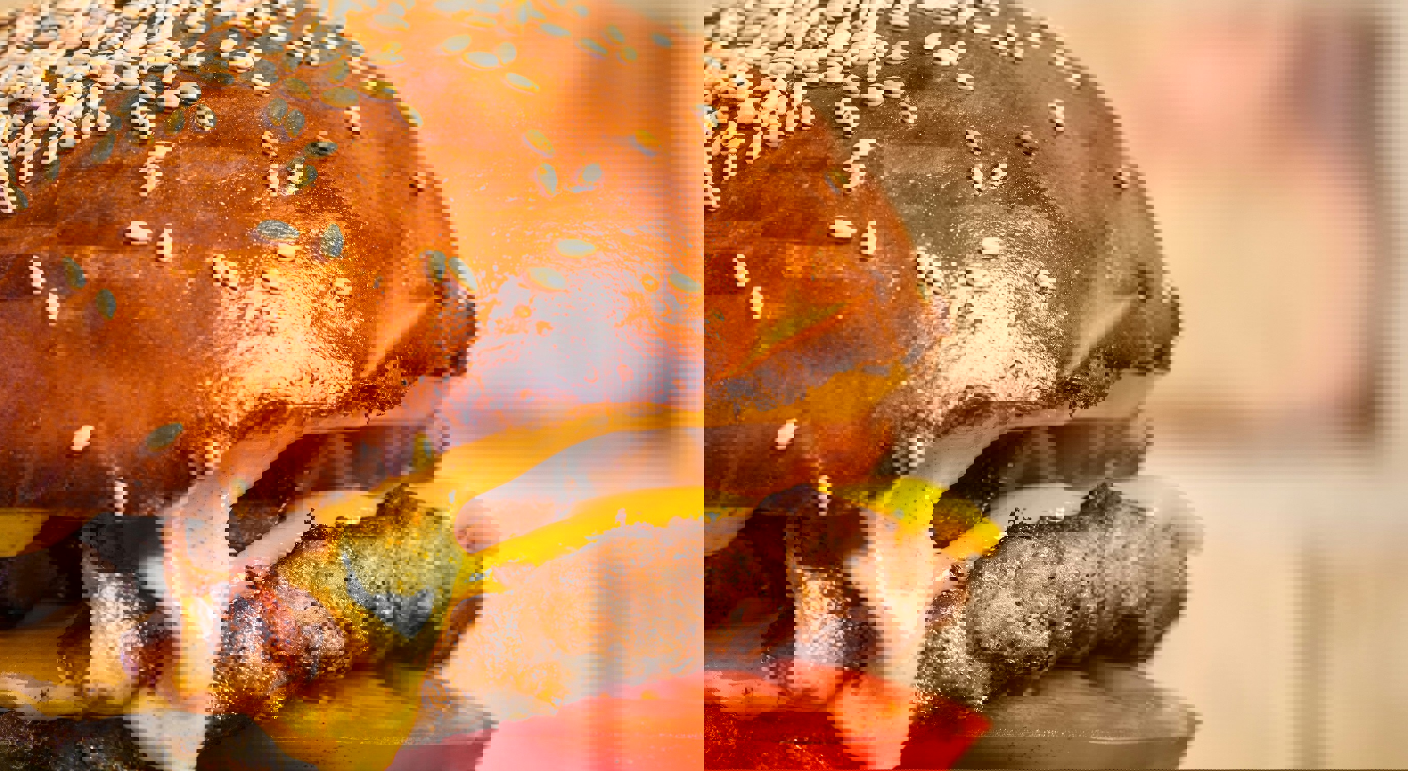 Juicy cheeseburger with lettuce, tomato, onion, and melted cheese on a sesame seed bun, secured with a skewer, set against a brick background