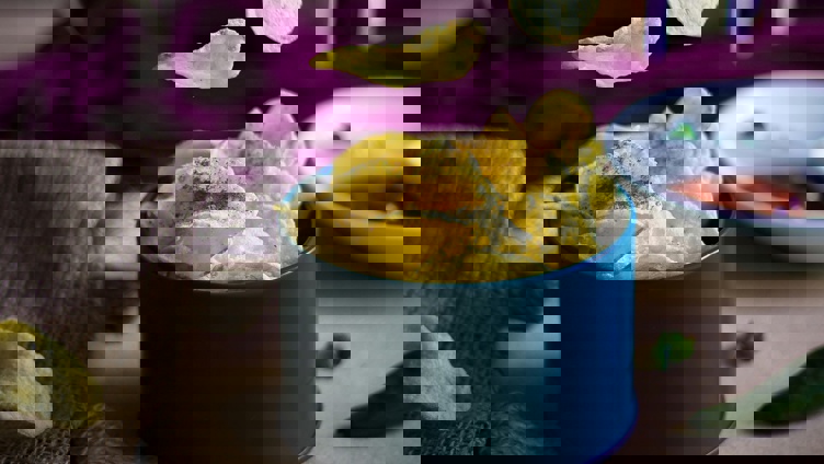 Potetgull i en blå bolle med chips flytende i luften, omgitt av grønne paprikaer og dip i bakgrunnen