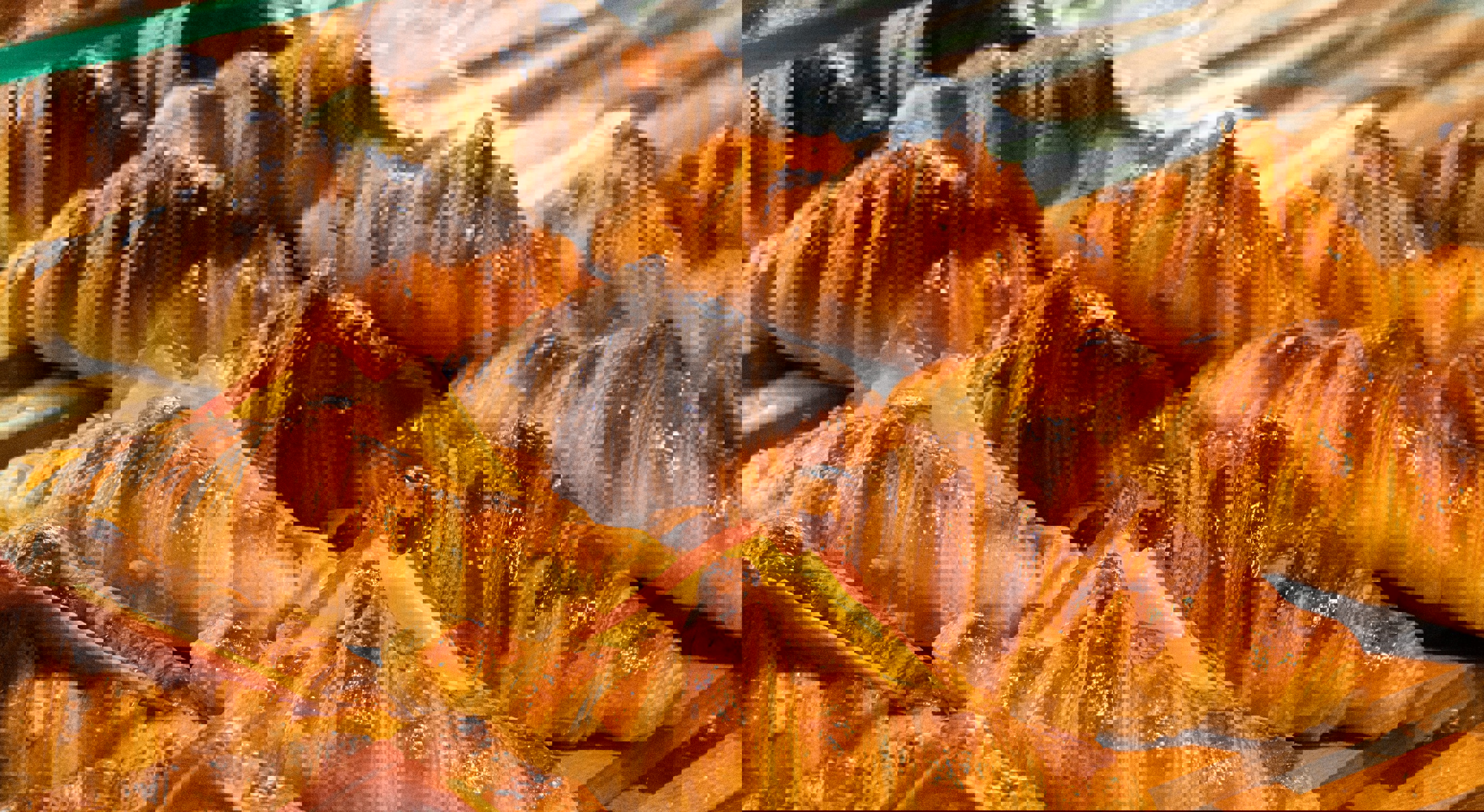 Freshly baked croissants with ham and cheese filling displayed on a wooden tray