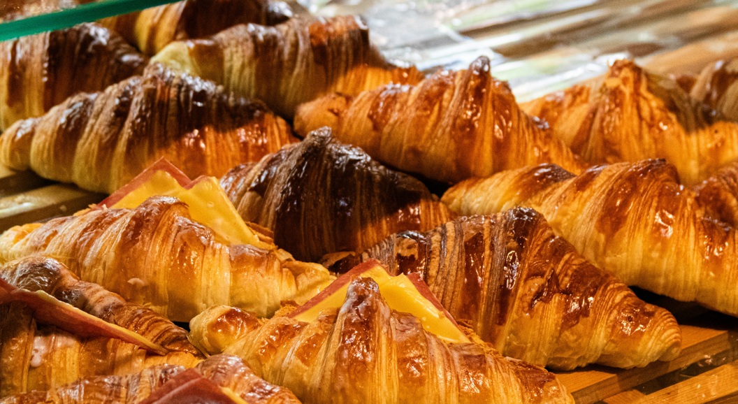 Nystekte croissanter med skinke- og ostefyll lagt frem på et trebrett