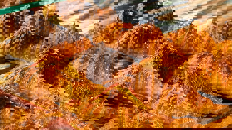 Nystekte croissanter med skinke- og ostefyll lagt frem på et trebrett