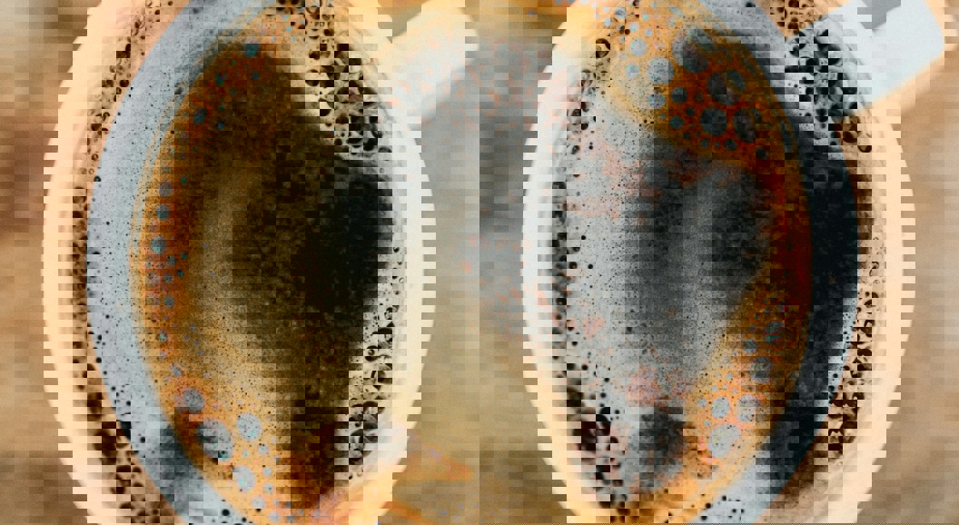 Oversikt over en rykende svart kaffe i en hvit kopp på et rustikt trebord