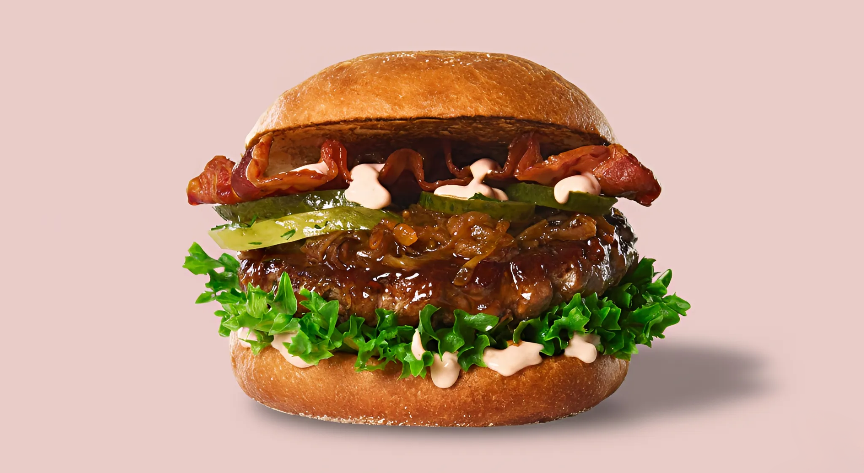Saftig burger med bacon, karamellisert løk, salat, sylteagurk og dressing.