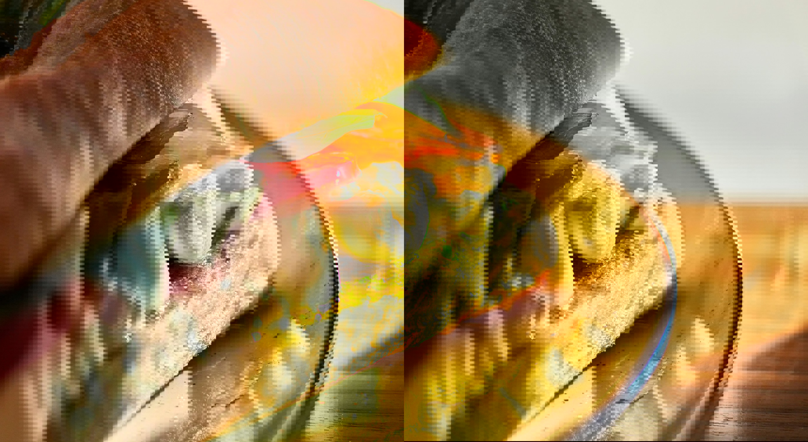 Fersk sandwich med mozzarella, tomater, basilikum og pesto på en tallerken i varm sollys