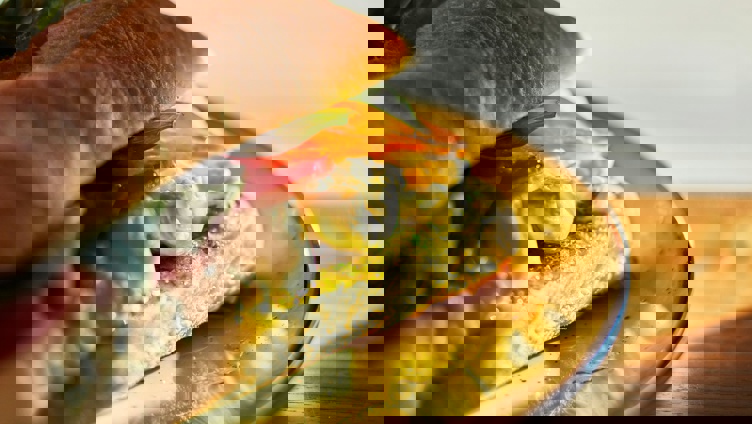 Fersk sandwich med mozzarella, tomater, basilikum og pesto på en tallerken i varm sollys