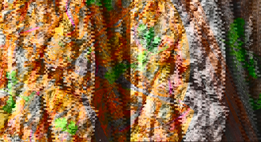 Gourmet barbecue chicken pizza with pineapple, red onion, cilantro, and melted cheese on a rustic wooden board