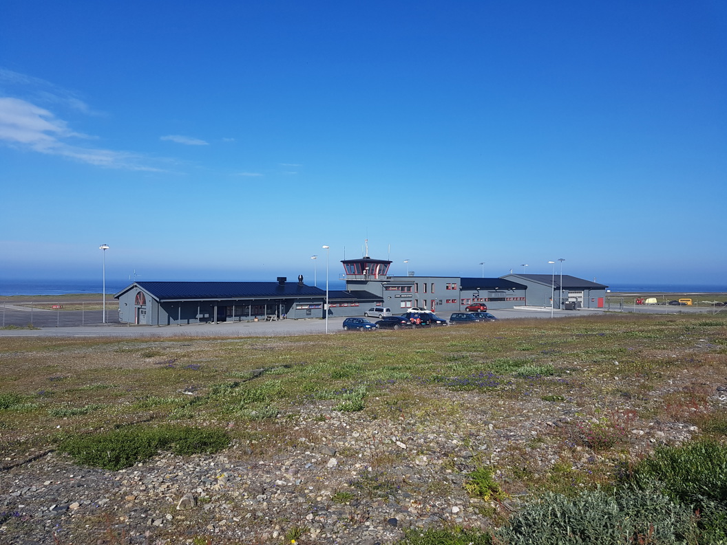 Berlevåg flyplass med kontrolltårn på øde landskap, blå himmel i bakgrunnen.