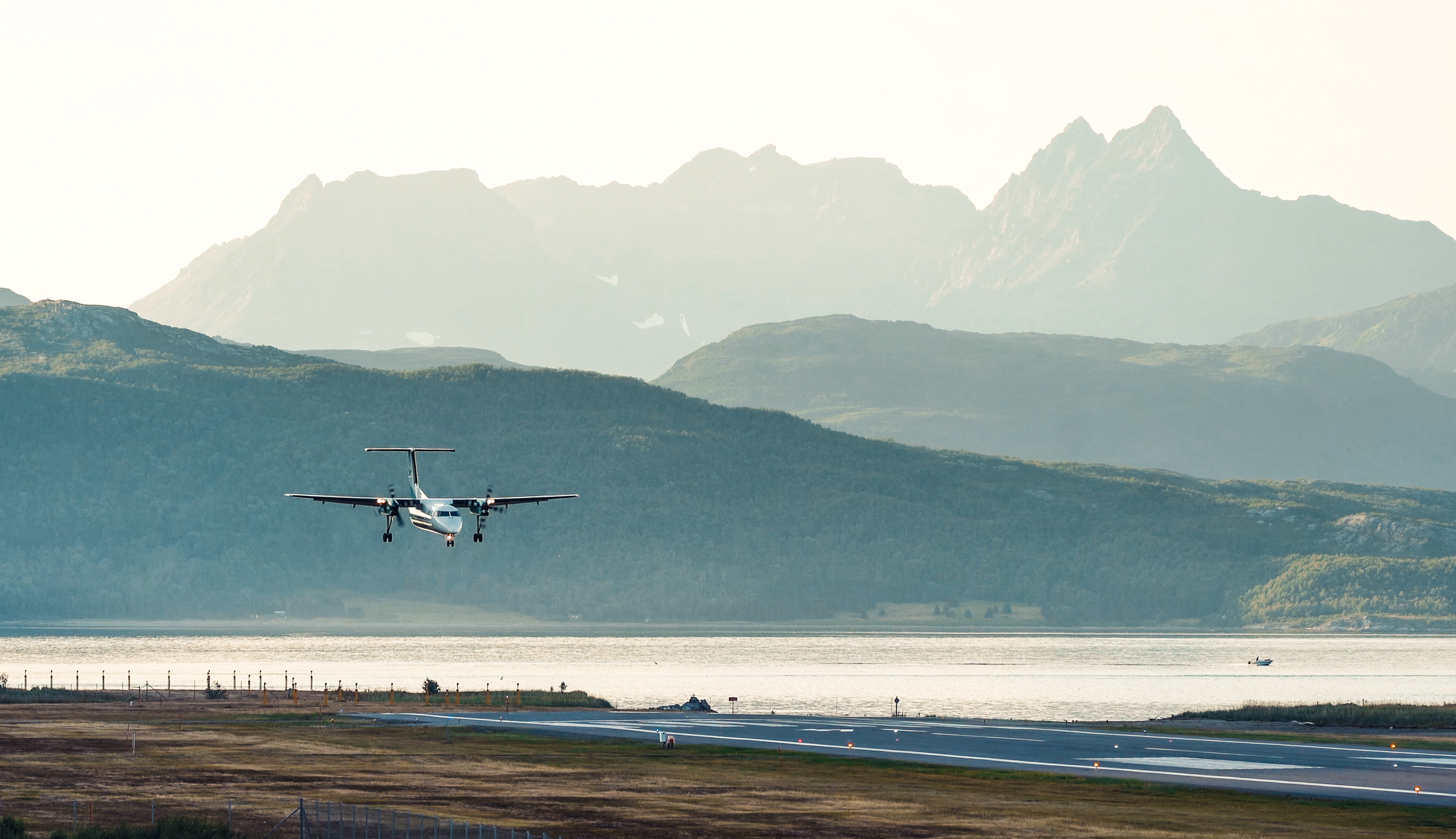 Flyet landar på Sørkjosen flyplass med fjell i bakgrunnen.