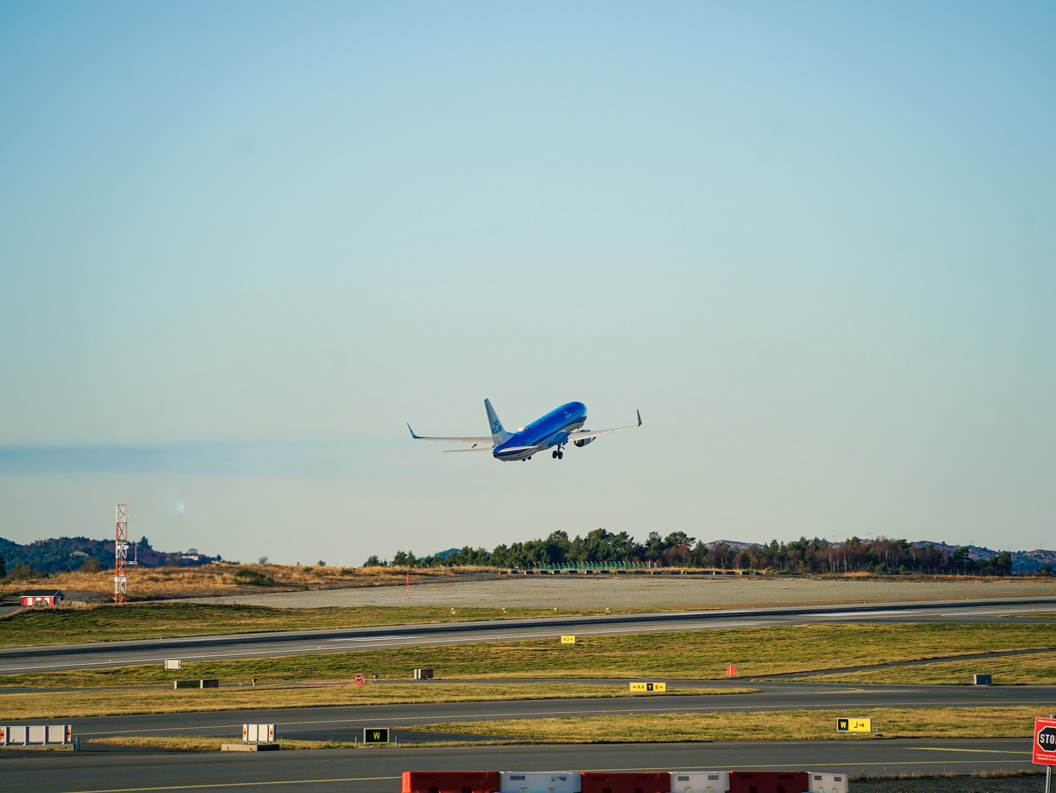 Passasjerfly tek av på flyplass med blå himmel i bakgrunnen