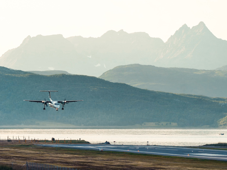 Airliner lands at Senja airport with majestic mountains in the background, Norway.