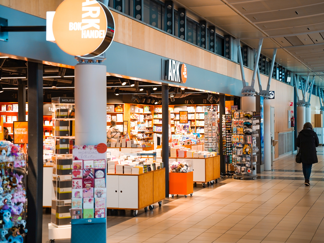 Kvinne blar gjennom fargerike barnebøker på en hylle i en bokhandel