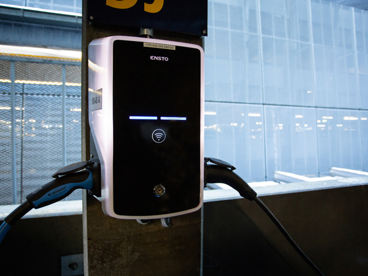 Electric vehicle charging station in a parking garage with visible cables and illuminated indicators, showcasing modern EV infrastructure