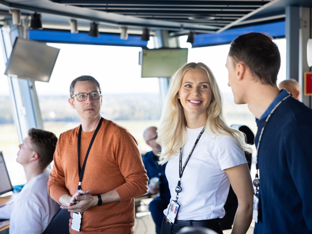 Air traffic control team at work in a modern control tower, discussing flight operations and monitoring screens