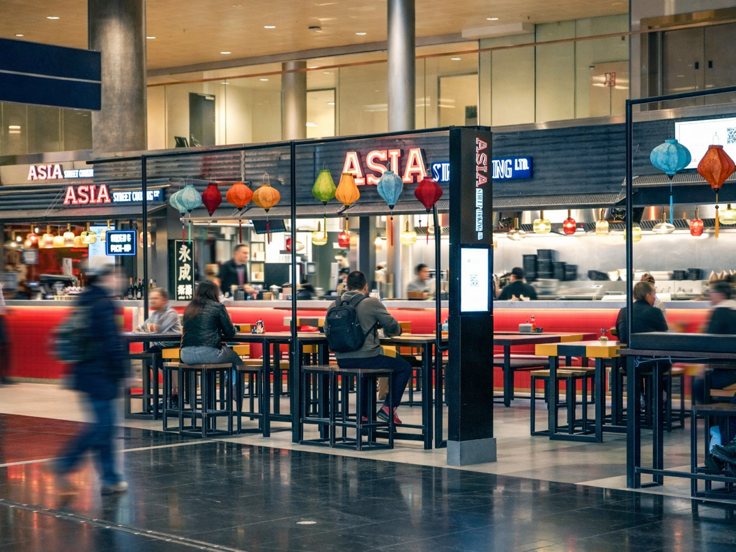 Gatekjøkken med asiatisk mat i fargerik innredning, med skilt for bestilling og henting. Moderne design med røde fliser og trebenker