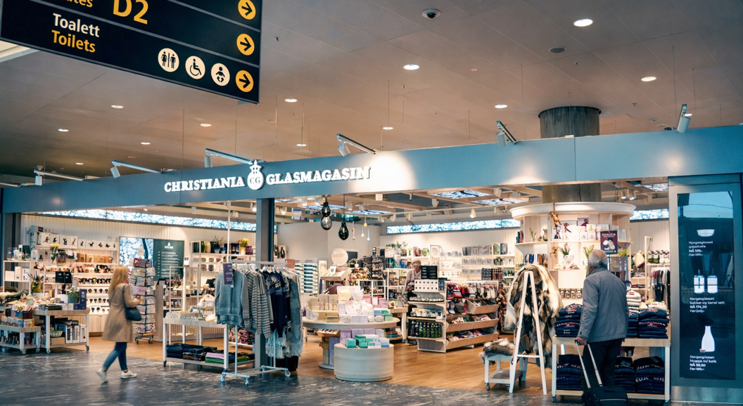 Butikken til Christiania Glasmagasin med et godt opplyst utstillingsvindu med smykker, klær og interiørartikler i et moderne kjøpesentermiljø