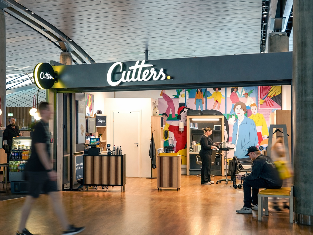 Smilende frisør med saks på en salong, klar til å jobbe med en klients hår