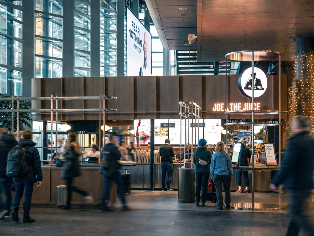 Nylaget sandwich med avocado og tomat, servert med en skummende appelsinjuice i en Joe & The Juice-merket kopp